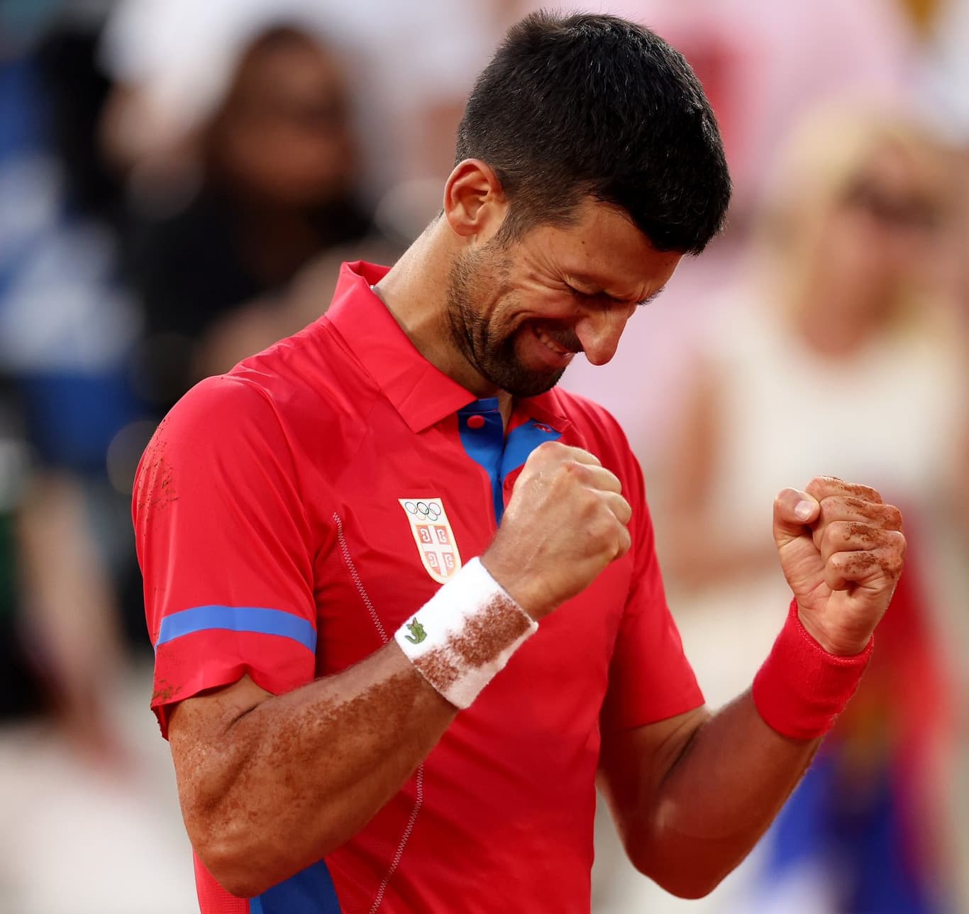 Novak Djokovic celebra con el escudo de Serbia tras un partido, representando su lucha de ideales.