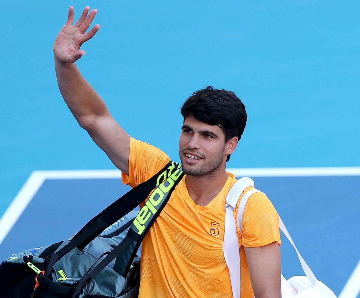 Carlos Alcaraz sonriente durante su visita al Premier Padel en Miami, compartiendo con jugadores profesionales de la disciplina. Leyenda: **¿Nueva Pareja?** Alcaraz confía en su nivel de pádel junto a Jannik Sinner.