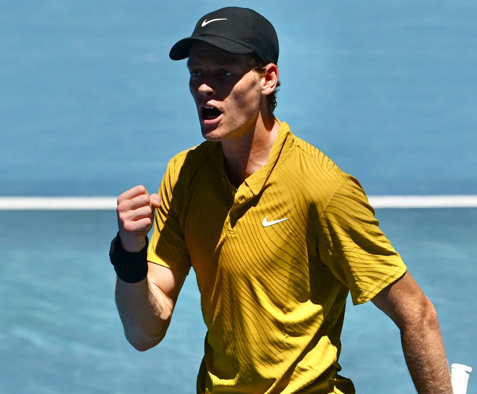 Jannik Sinner gritando con el puño cerrado tras ganar un punto crucial, con su equipación amarilla de la temporada 2026.
