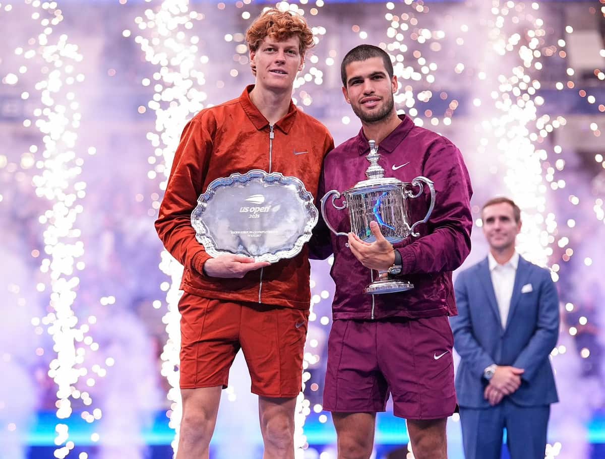 Jannik Sinner y Carlos Alcaraz posando con trofeos de Grand Slam.