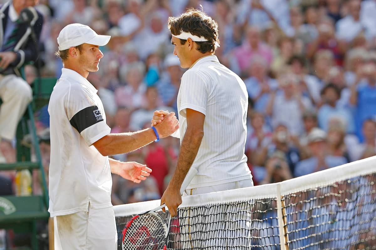 Andy Roddick y Roger Federer dándose la mano en la red tras una final de Grand Slam, reflejando el respeto y la rivalidad.