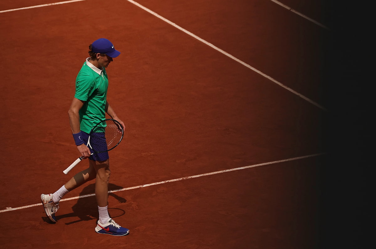 Jannik Sinner analizando el horizonte en una pista de tierra batida, representando su enfoque táctico.