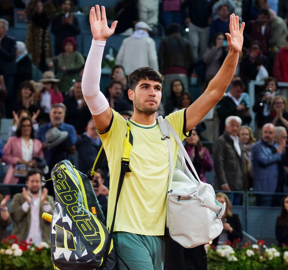 Carlos Alcaraz se despide de la afición en Madrid con gesto de tristeza y una manga de compresión en su brazo derecho tras retirarse por lesión.