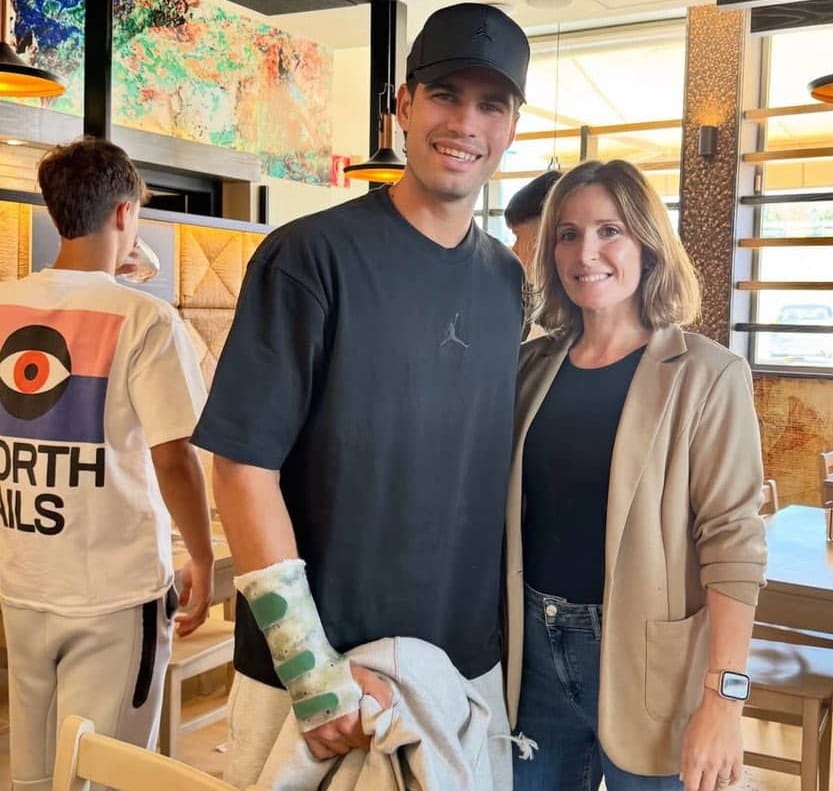 Detalle de la muñeca de Carlos Alcaraz protegida por una férula de inmovilización mientras posa con una aficionada.