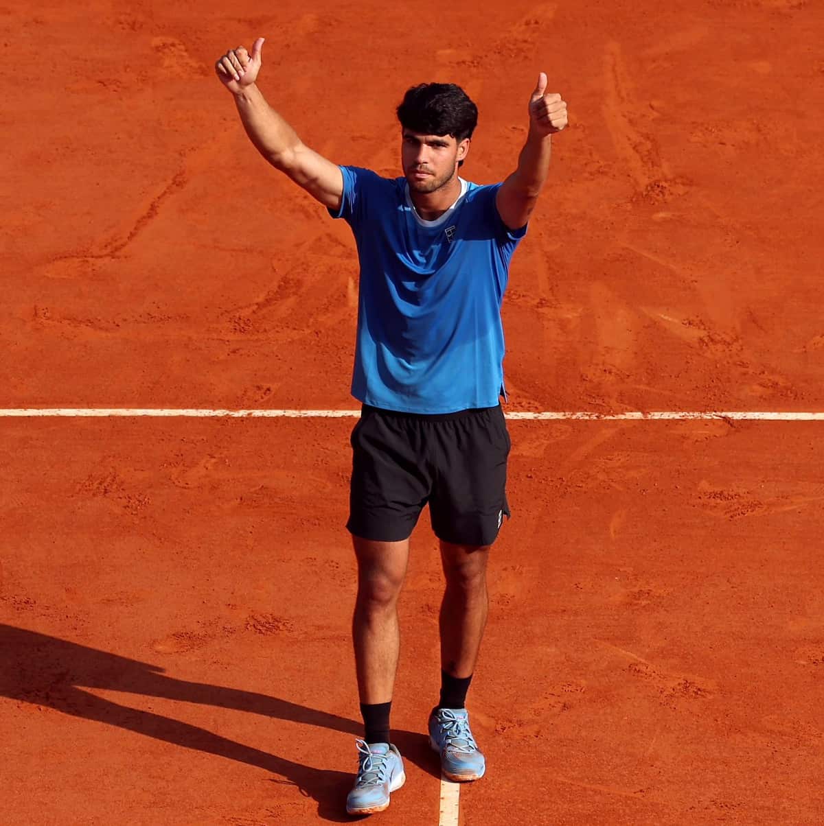 Carlos Alcaraz realizando un drive potente en tierra batida, con una imagen traslúcida de Rafa Nadal celebrando en Roland Garros al fondo.
