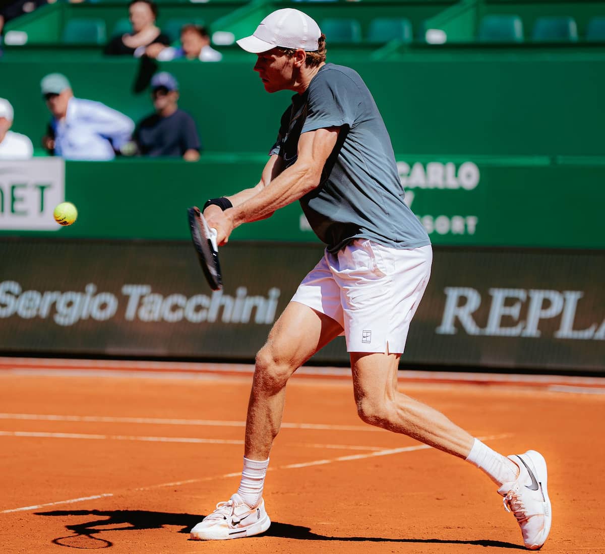 Jannik Sinner ajustando su raqueta con mirada gélida y enfocada durante las sesiones de entrenamiento en el Country Club de Mónaco.
