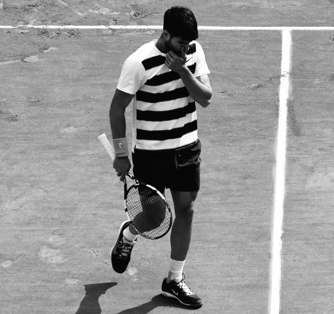 Carlos Alcaraz con la cabeza baja y gesto de frustración, representando su renuncia oficial a los torneos de Roma y Roland Garros 2026.