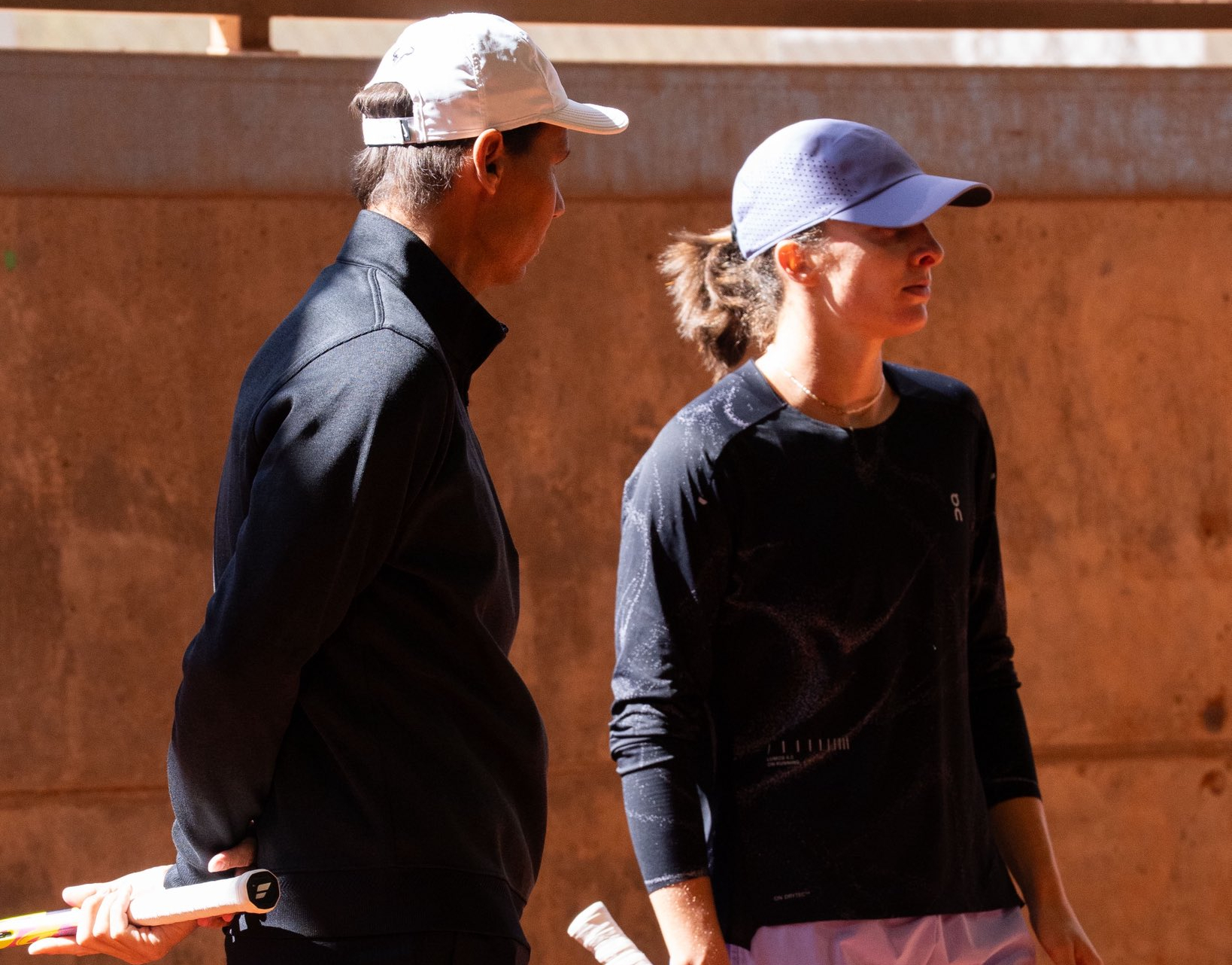 Rafael Nadal gesticulando y explicando el movimiento de empuñadura y terminación de su derecha a una atenta Iga Swiatek.
