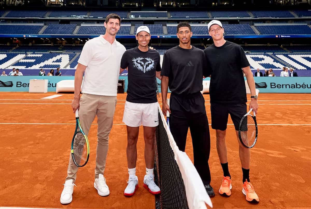 Rafael Nadal golpeando una derecha en la pista de tenis instalada sobre el césped retráctil del Estadio Santiago Bernabéu, con Jude Bellingham al fondo.
