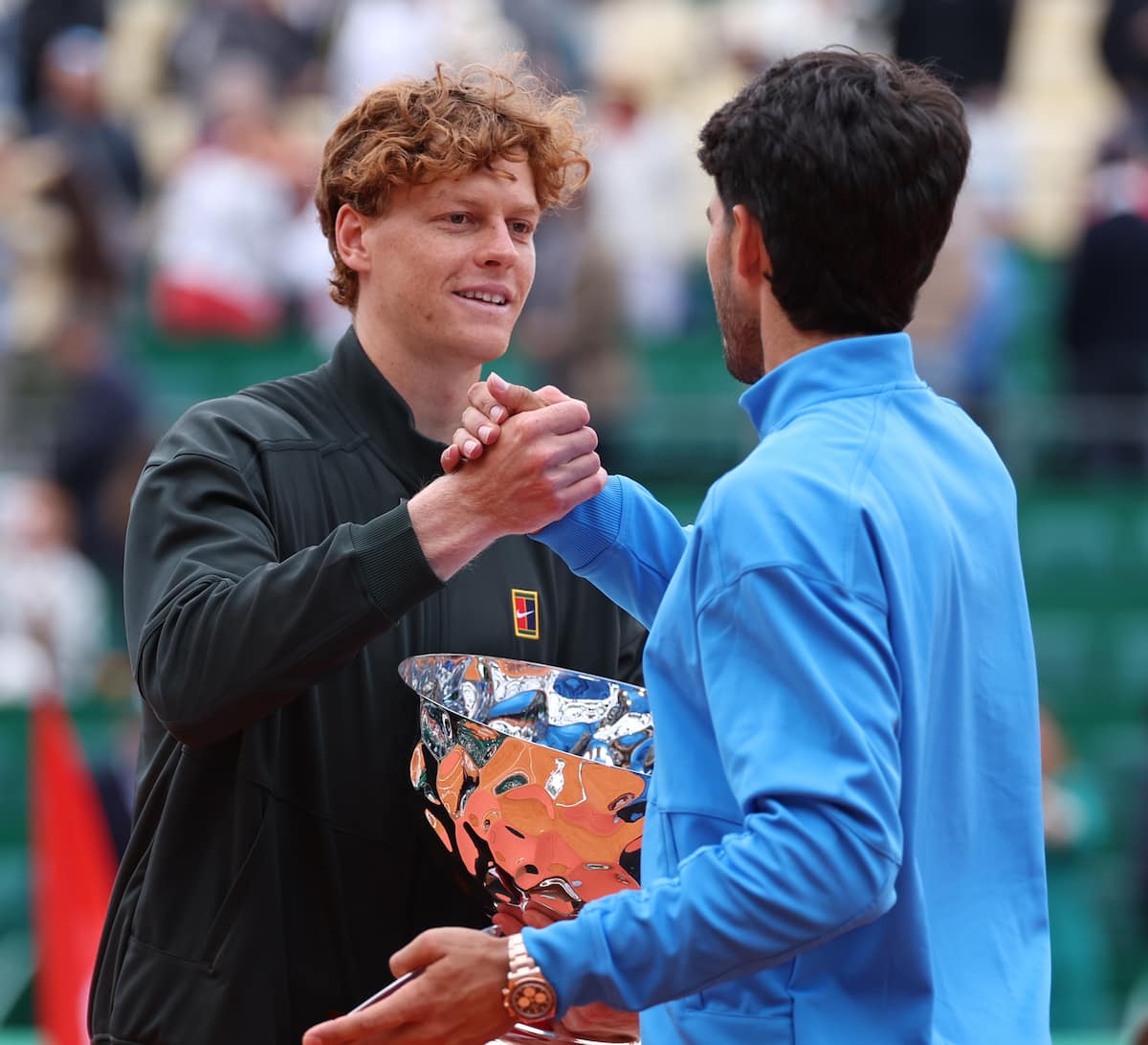 Jannik Sinner sostiene el trofeo de campeón mientras saluda a Carlos Alcaraz tras la final del Masters 1000 de Montecarlo 2026.